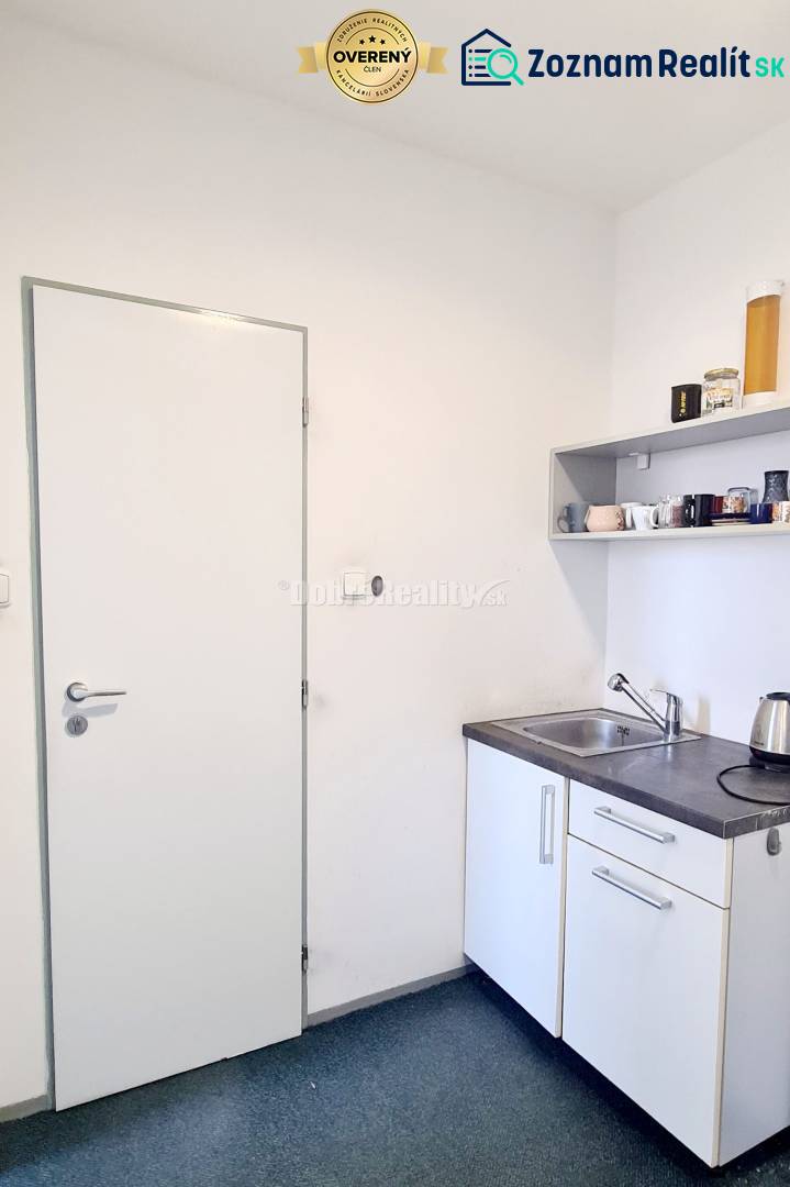 A small office kitchenette with a sink, a shelf, and a kettle.