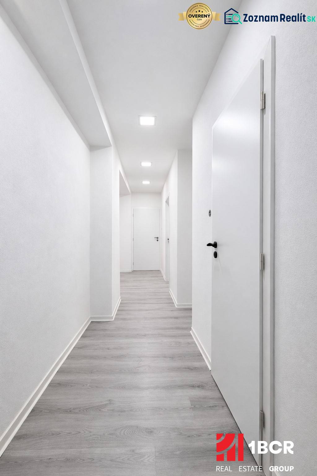 A hallway with white walls and a wooden decor floor in a 3-room apartment.