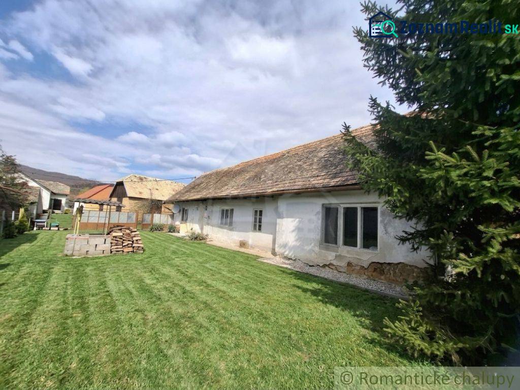 A family house in Ozdín with an original appearance and a grassy yard, surrounded by trees.