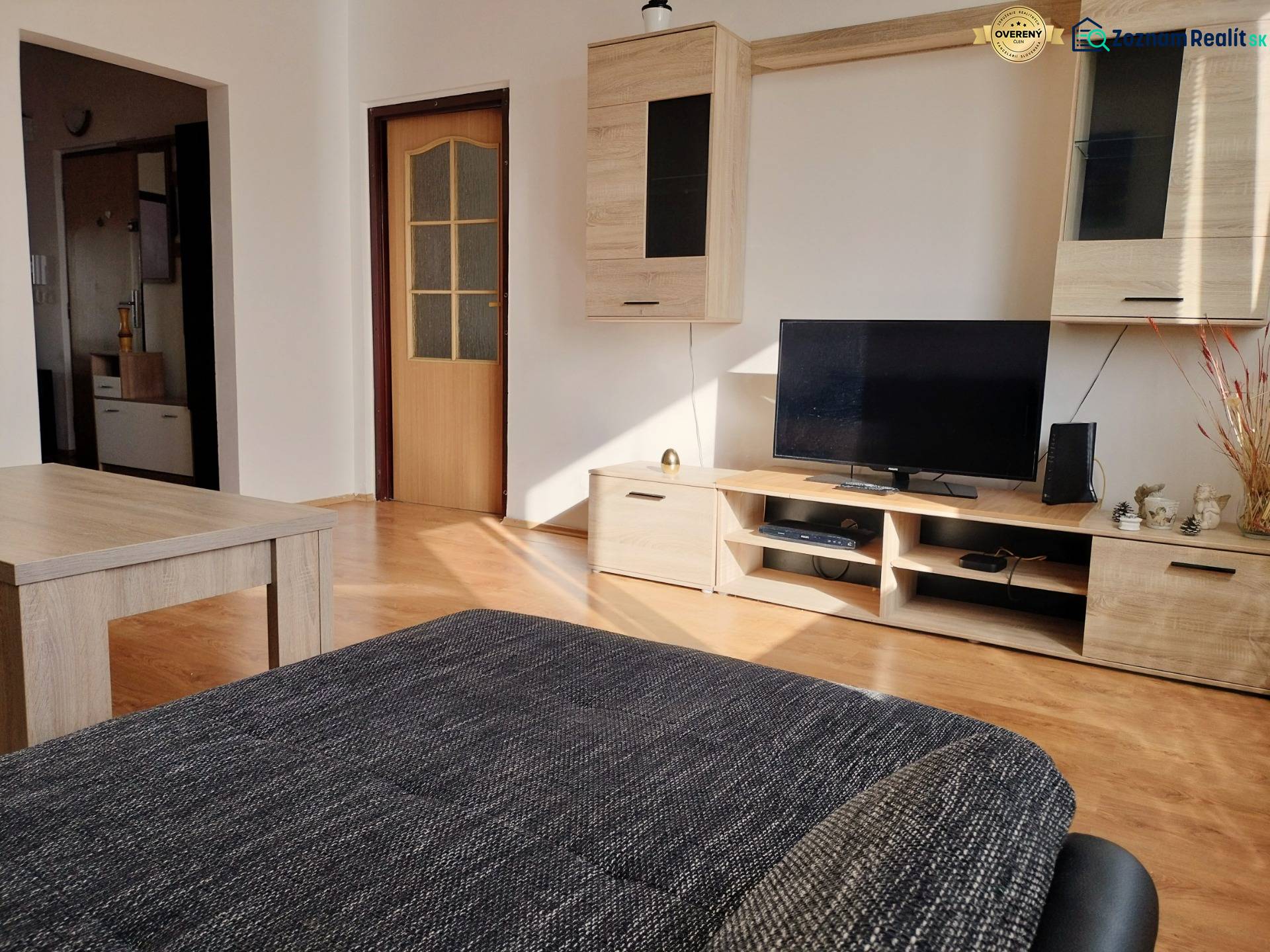 Living room in a 3-room apartment with a wooden decor floor, television, and furniture.