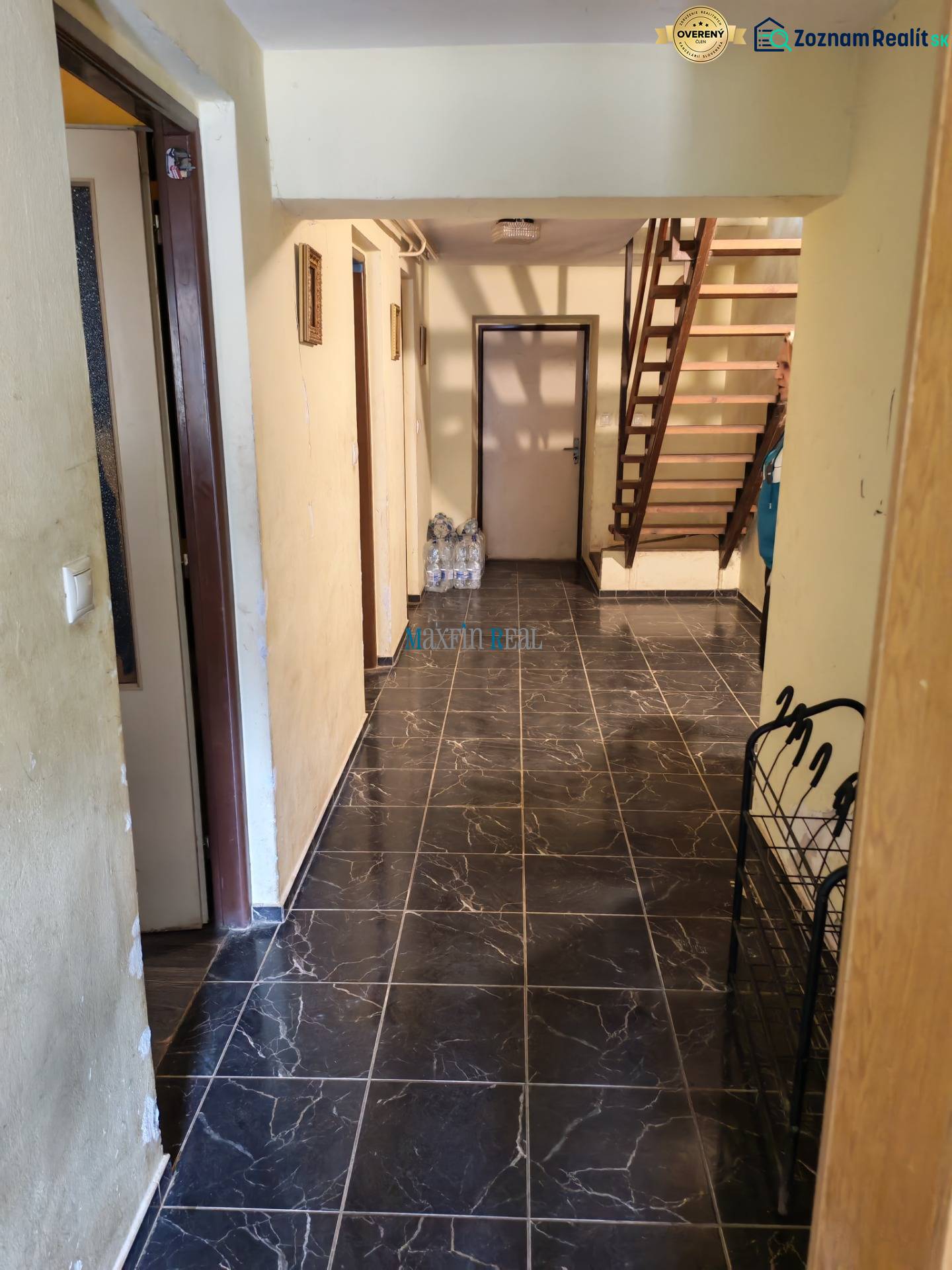 Interior of a family house with dark tiles and a wooden staircase.