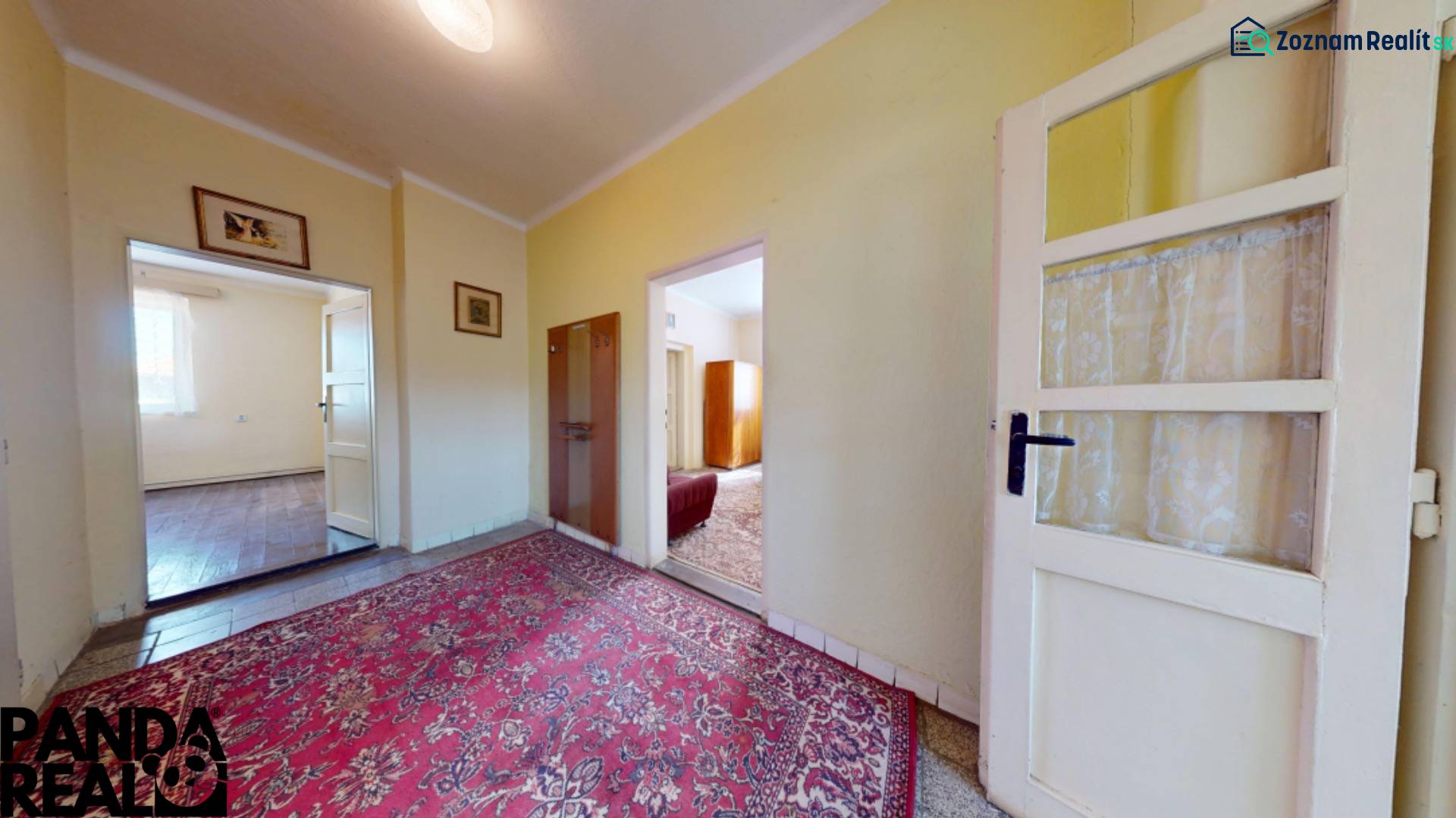 The hallway of a family house with a carpet and bright rooms.
