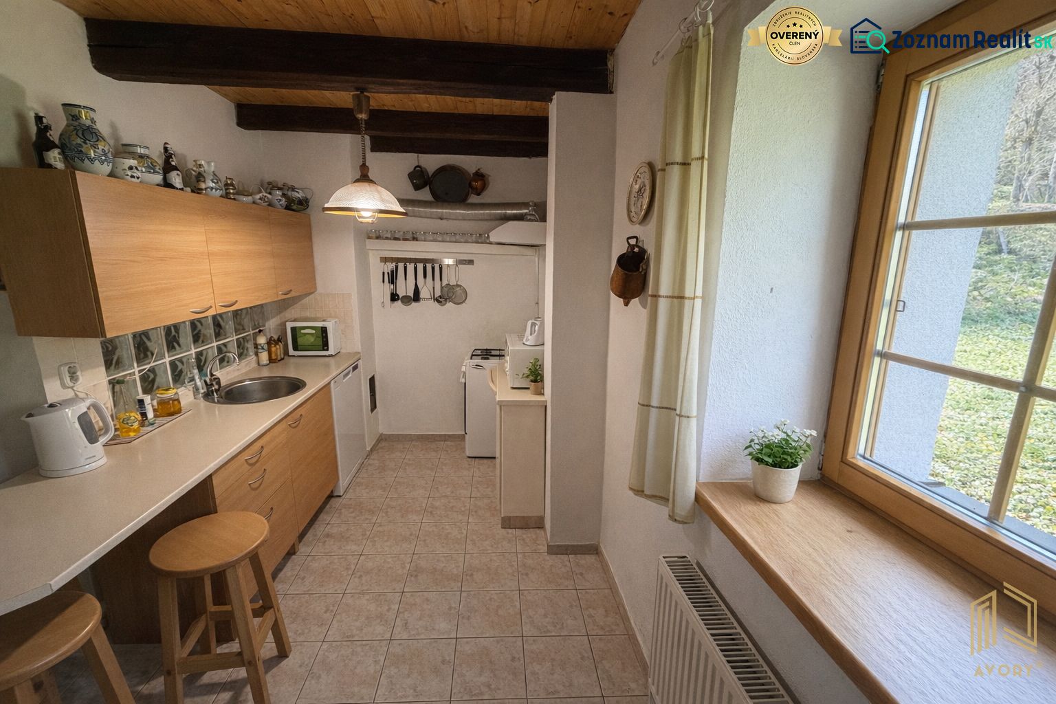 A kitchen with tiles in a family house with wooden beams and a fully equipped kitchenette.