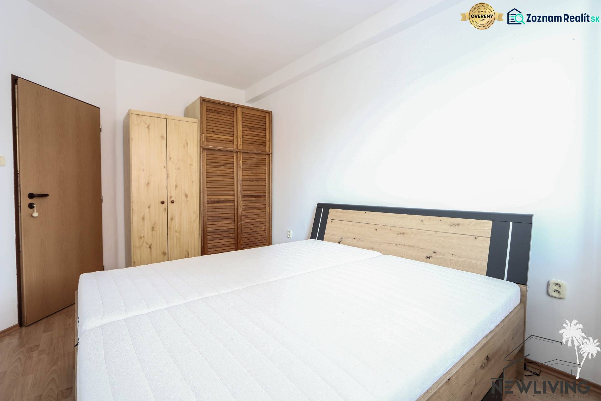 A bedroom in a 2-room apartment with a bed and wooden wardrobes, flooring with a wooden decor.