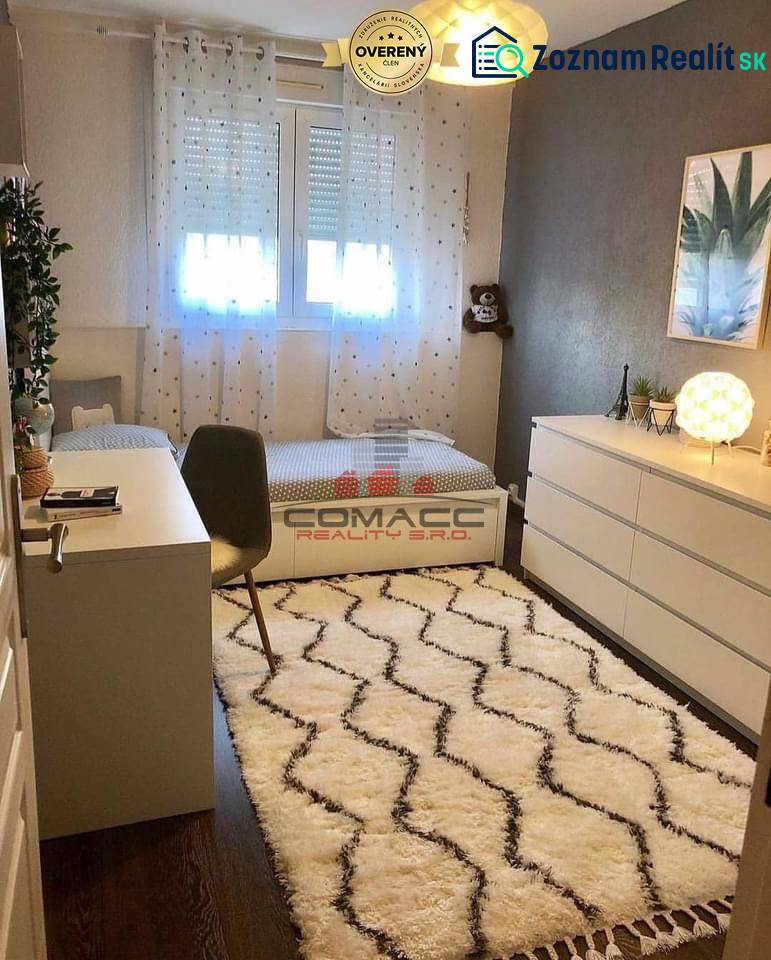 Children's room with a desk, carpet, and wooden decor flooring in a family house.