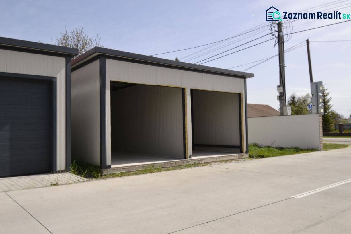 Garages in Michal na Ostrove with two open entrances, next to the road and the fence.