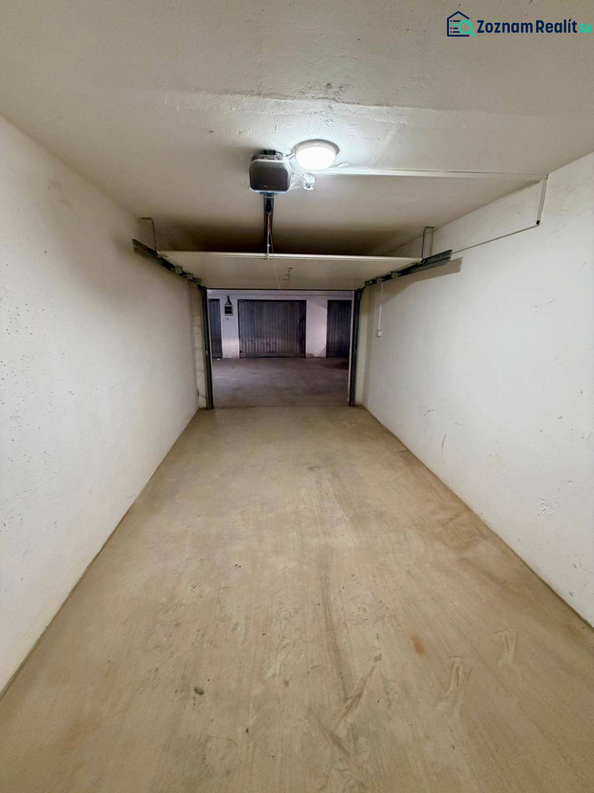 Closed garage space with a concrete floor and lighting.