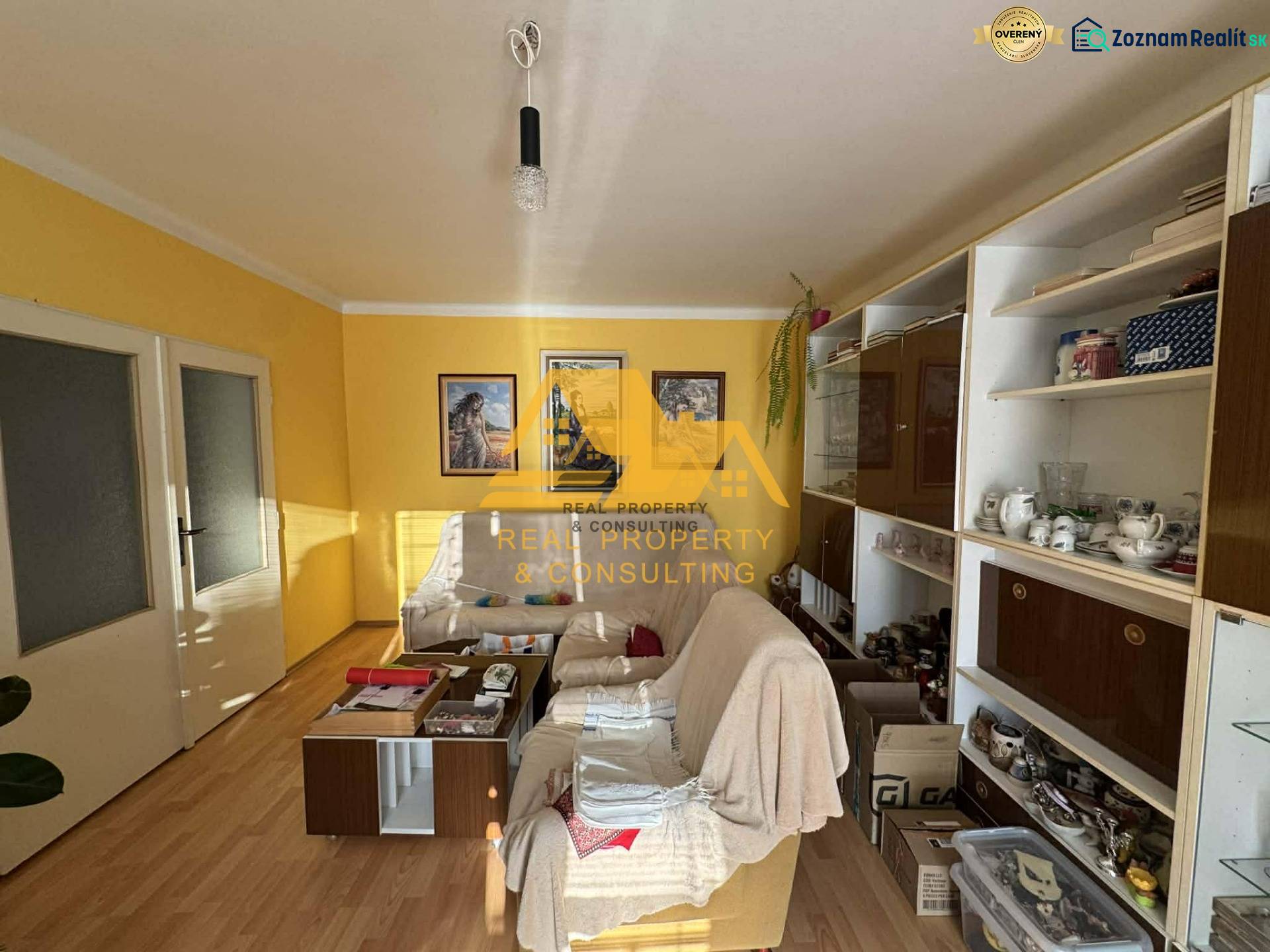 Living room in a family house with a white sofa, wooden decor flooring, yellow walls.