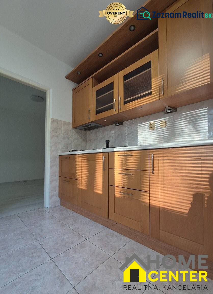 A kitchen unit in a studio apartment with tiles and cabinets with a wood decor.
