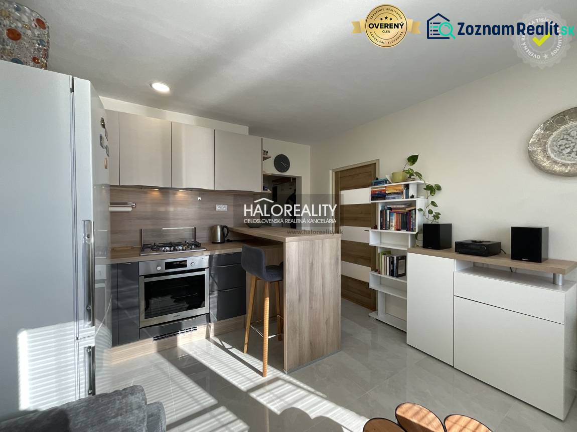 A kitchen in a studio apartment with a bright interior and a seating counter.