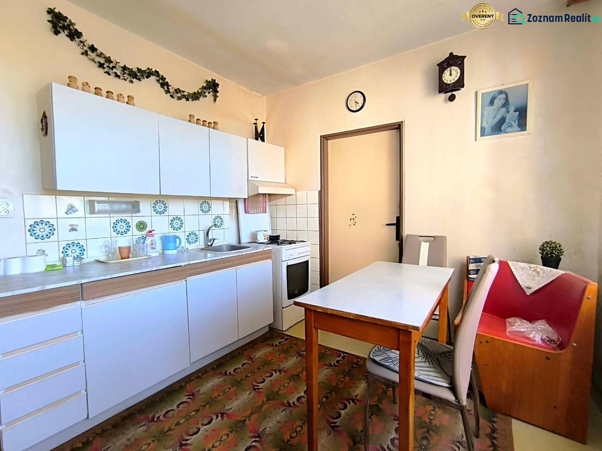 A kitchen in a 3-room apartment with white cabinets and decorative tiles.