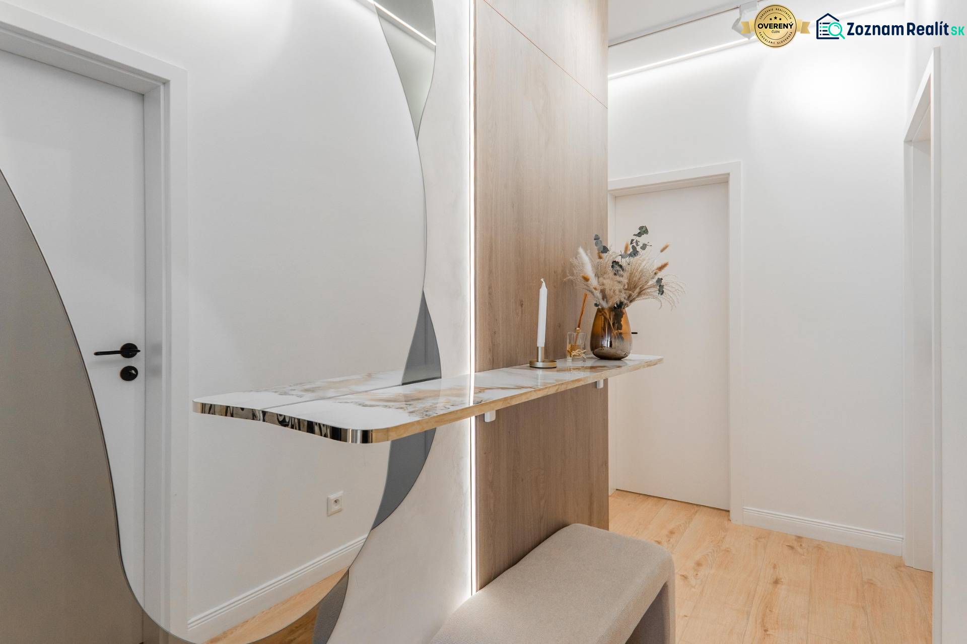 A hallway in a 3-room apartment with a minimalist table, mirror, and floor with a wooden decor.