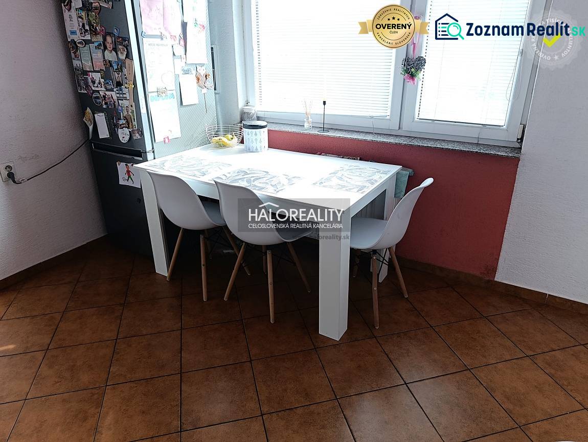 Kitchen of a 2-room apartment with a dining table, white chairs, and a window.