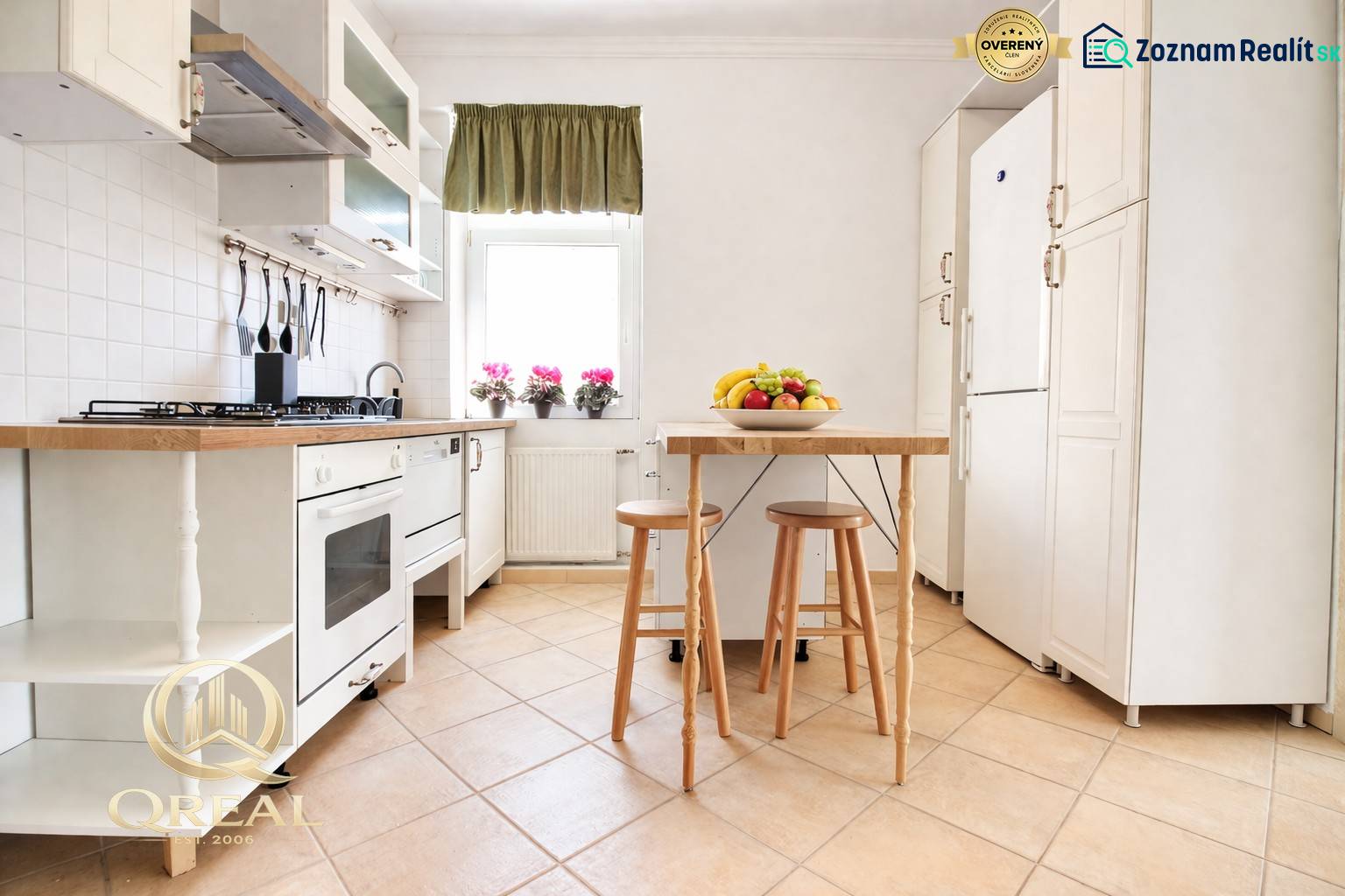 A kitchen in a studio apartment with white cabinets and a table with fruit.