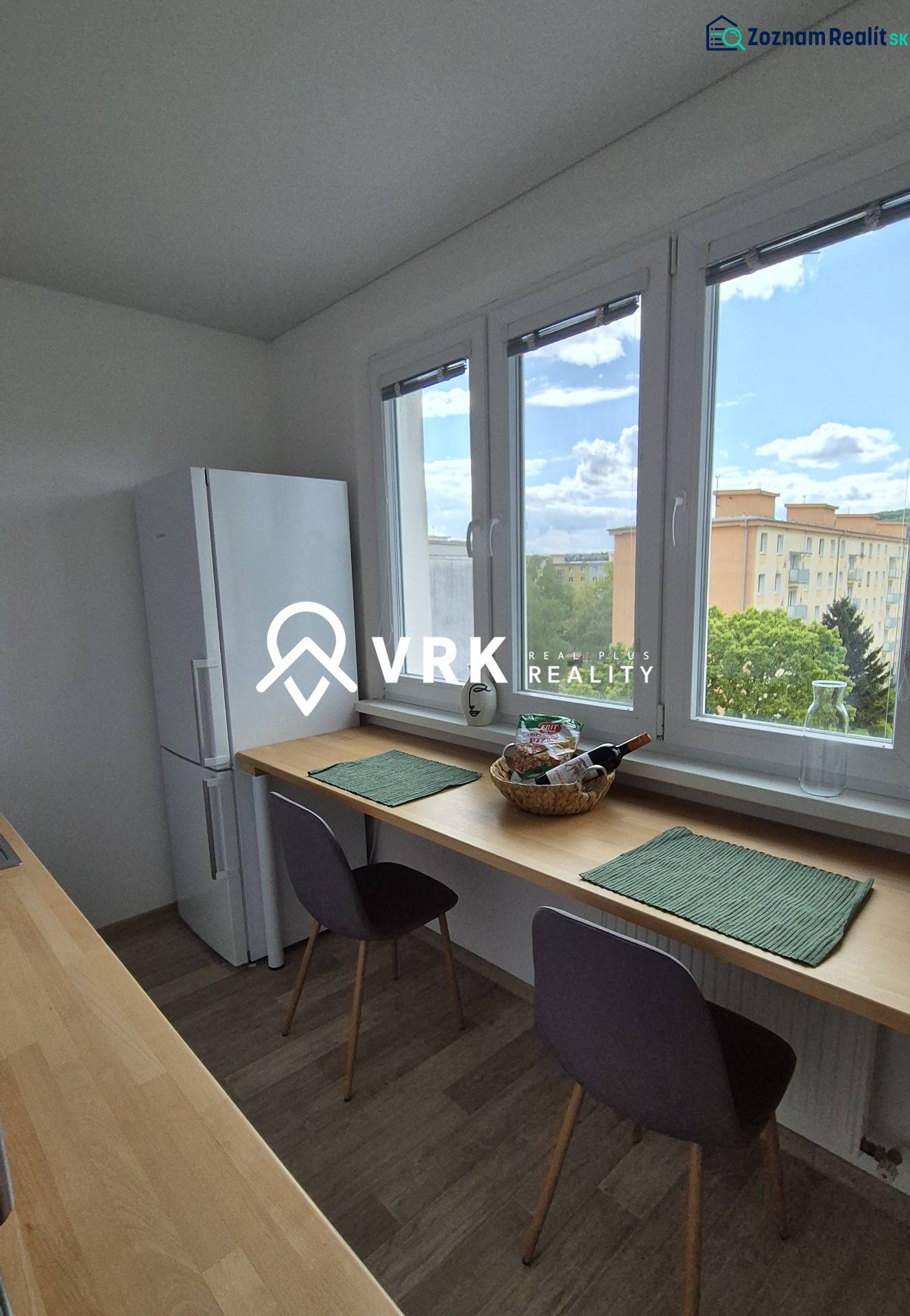 Kitchen corner with a table, chairs, and a refrigerator, view of the surrounding landscape.