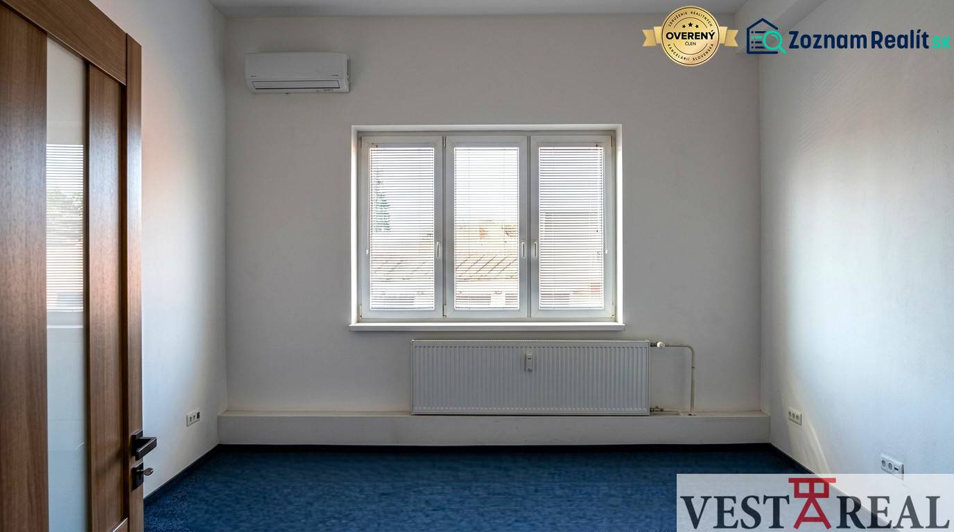 A room with air conditioning and a window in the offices, blue carpet, white walls.