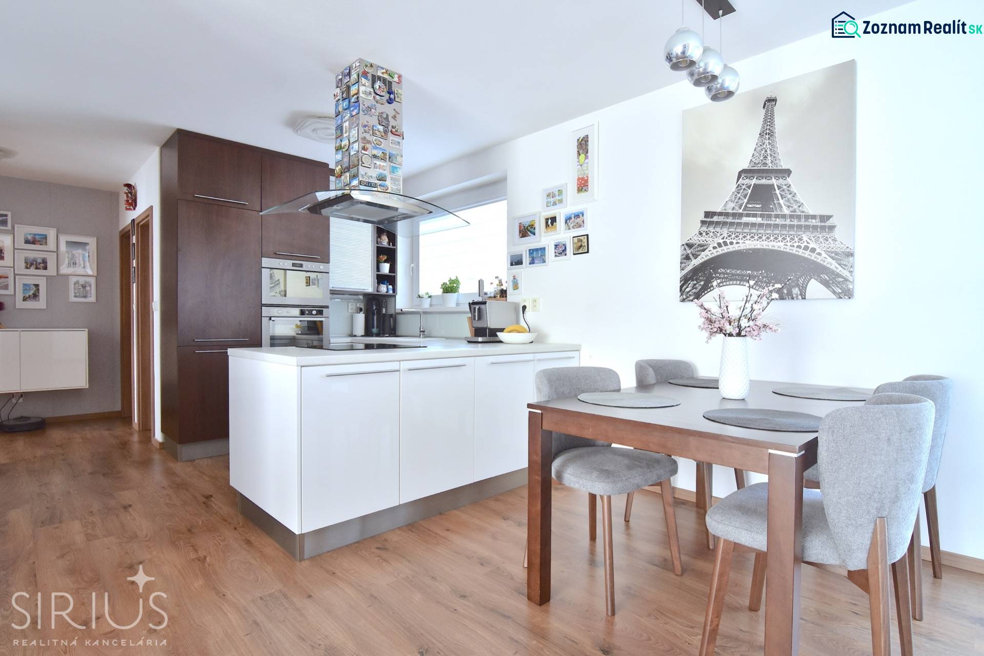 A kitchen in a 3-room apartment with a wooden decor floor and a dining table.