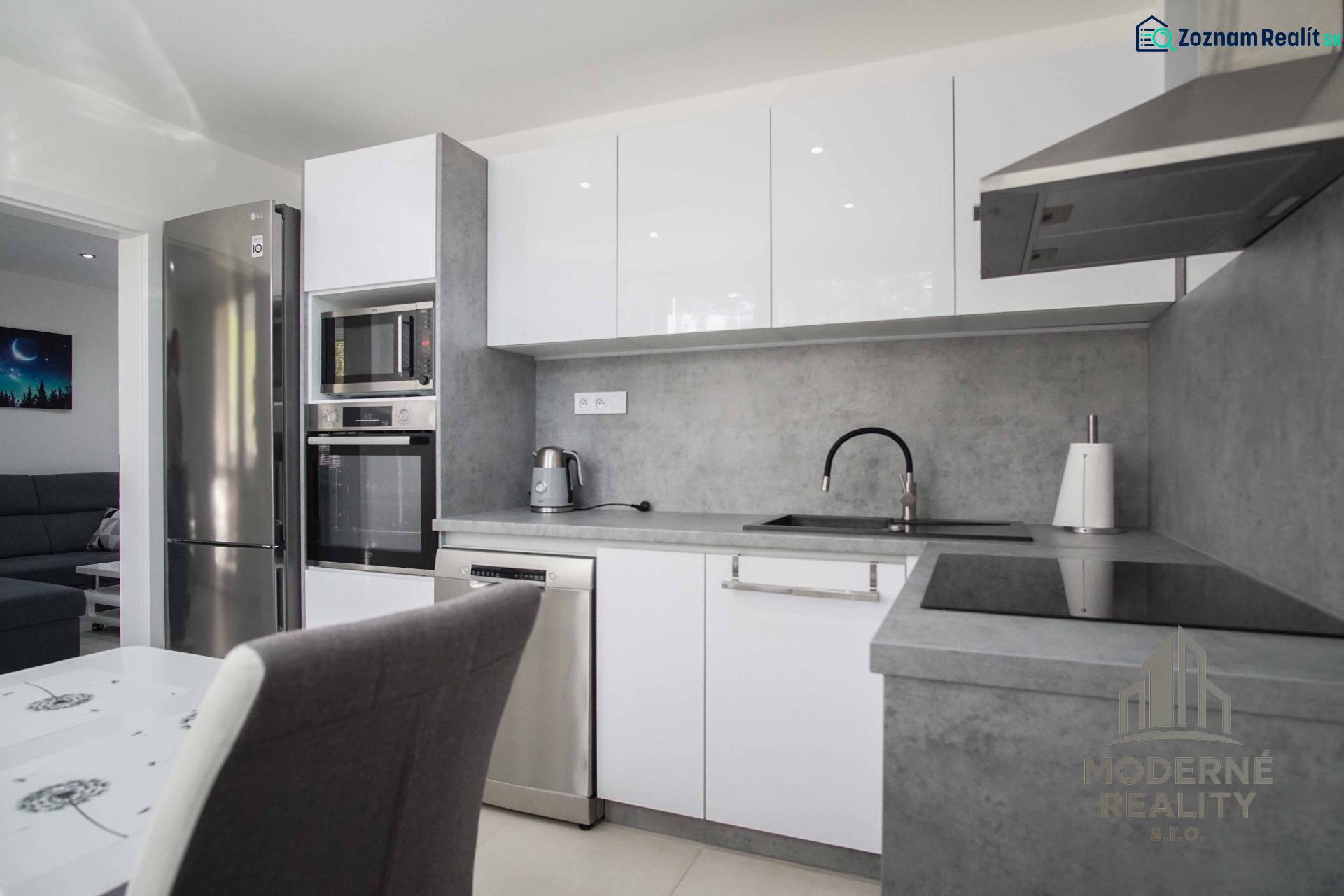 A kitchen in a 2-room apartment with stainless steel appliances and a gray countertop.