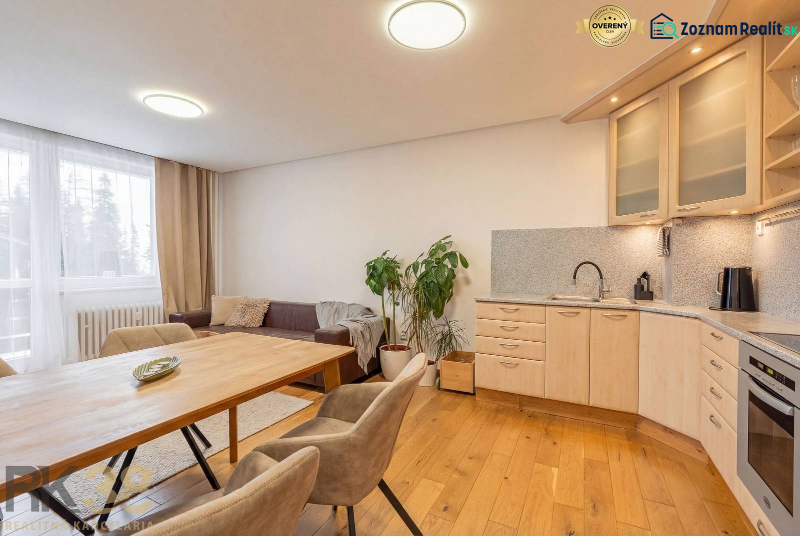 Interior of a vacation apartment with a sofa, kitchen, and wooden decor flooring.