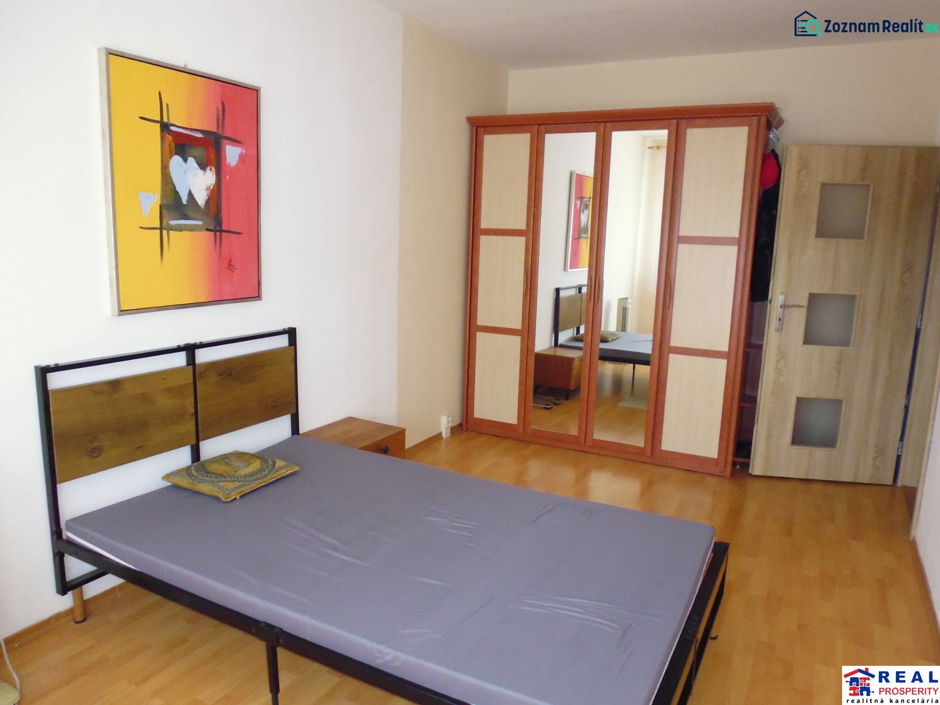 Bedroom with a bed, wooden decor flooring, and a wardrobe in a 2-room apartment.