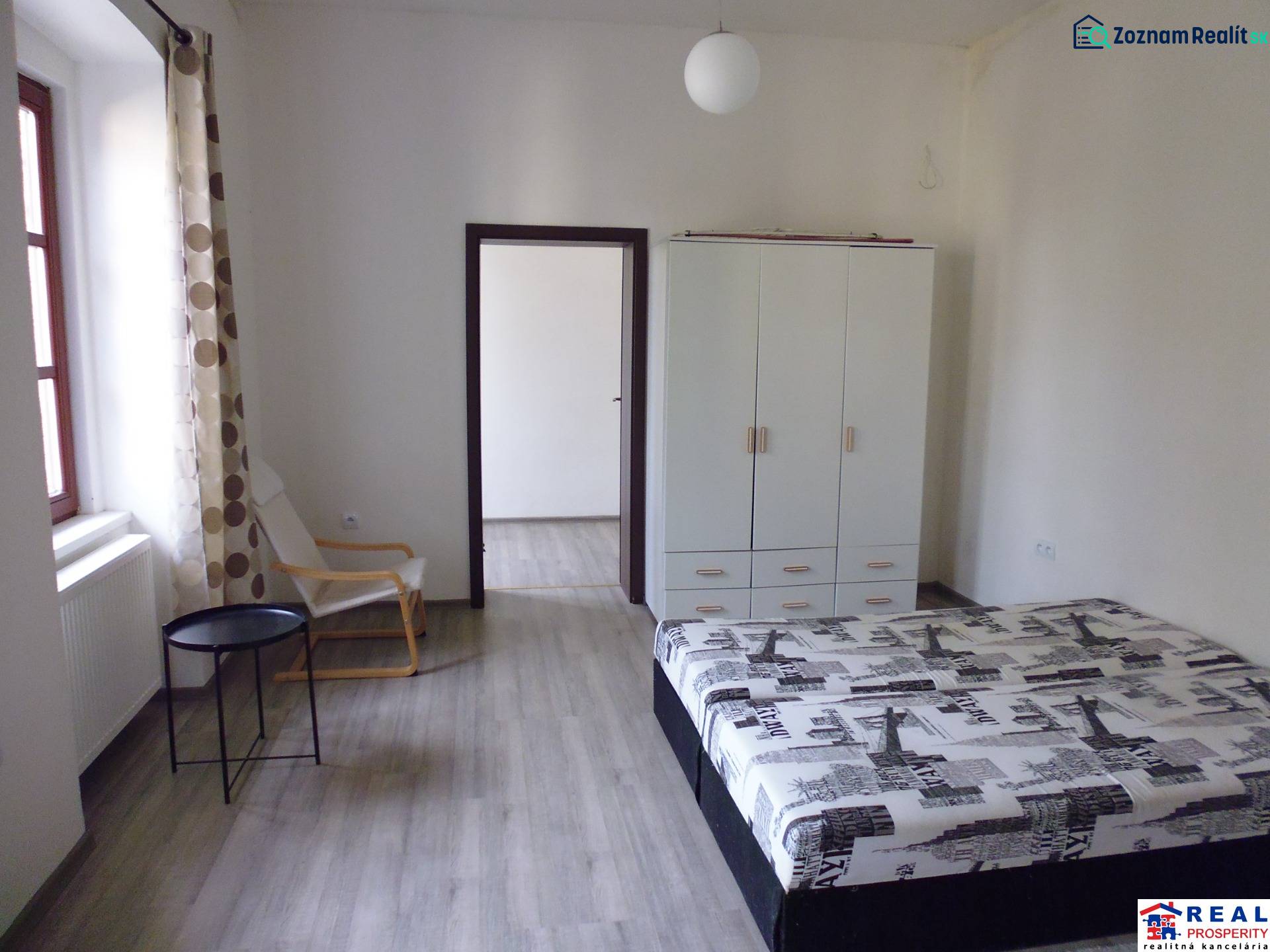 Bedroom in a 3-room apartment with wood-patterned flooring, a wardrobe, and a bed.