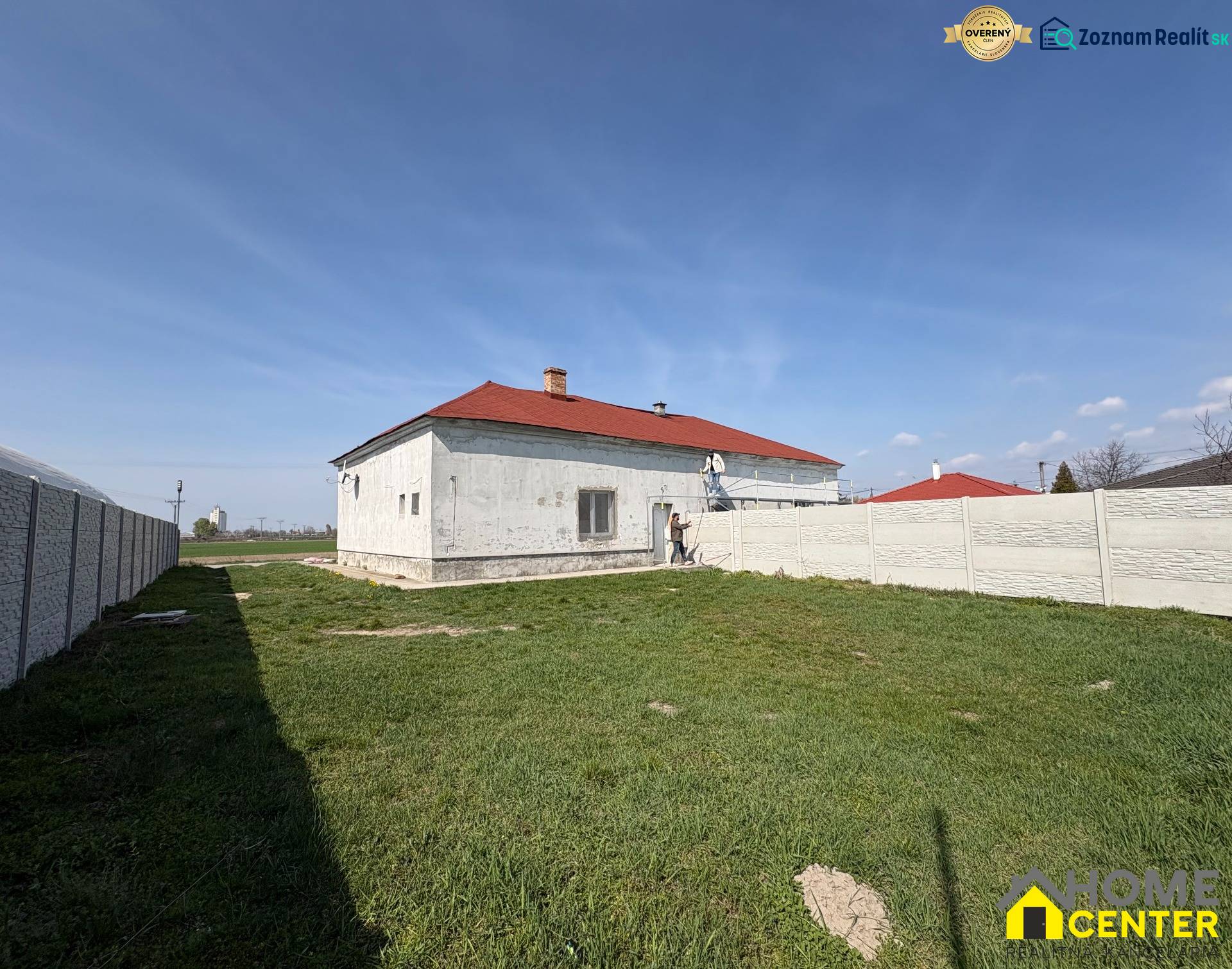A family house in Zemianska Olča with a white facade and a red roof on a grassy plot.