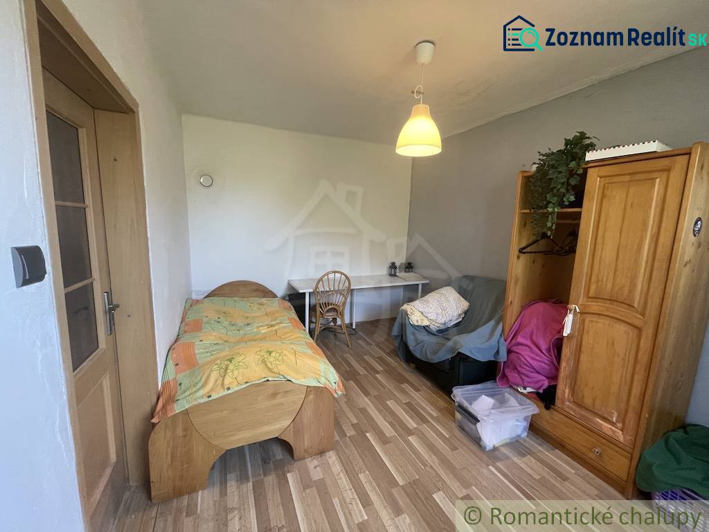 A room in a family house with a bed, a table, and a floor with a wooden decor.