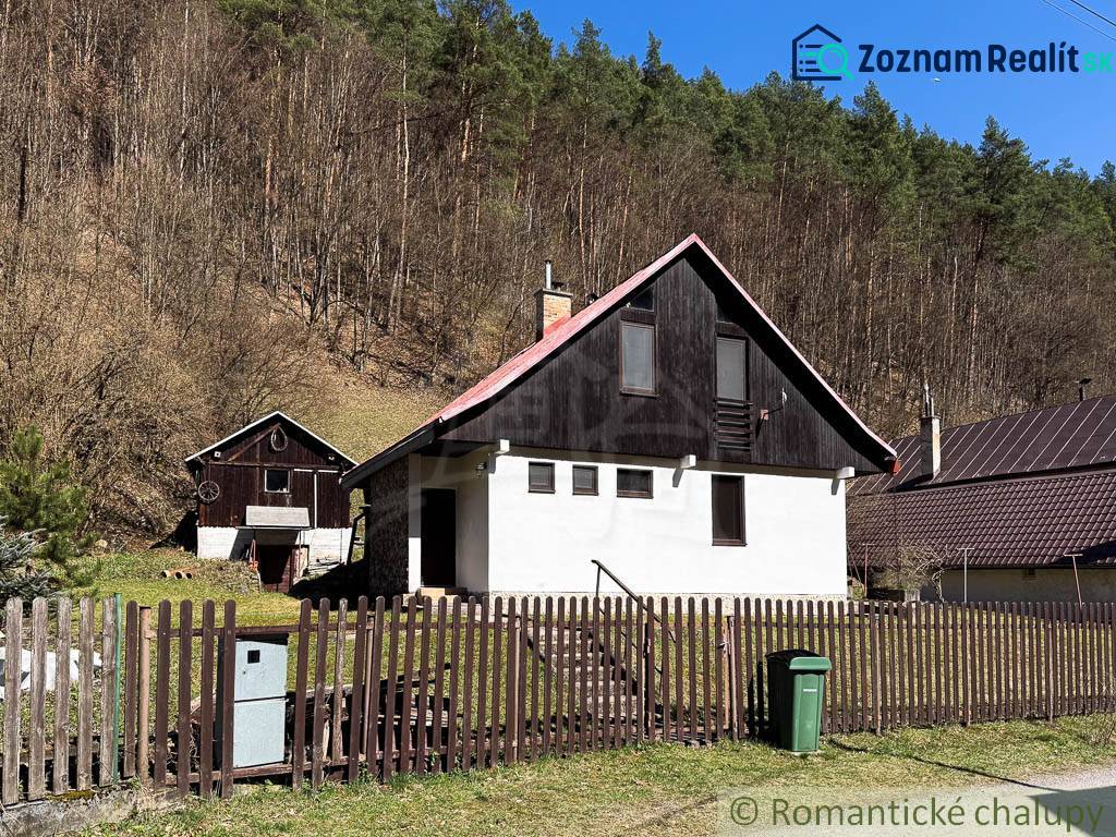 A cottage in Moštenica surrounded by forests, a fence and a trash can in the yard.
