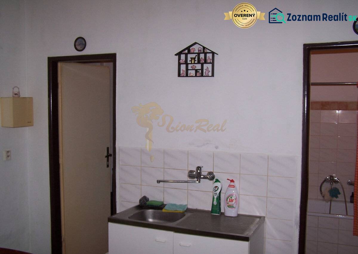 A kitchenette with a hanging dish rack by the sink in a 2-room apartment.