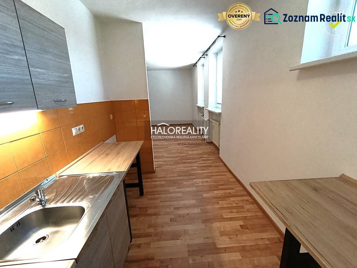 A kitchen in a 2-room apartment with a wooden decor floor and orange tiles.