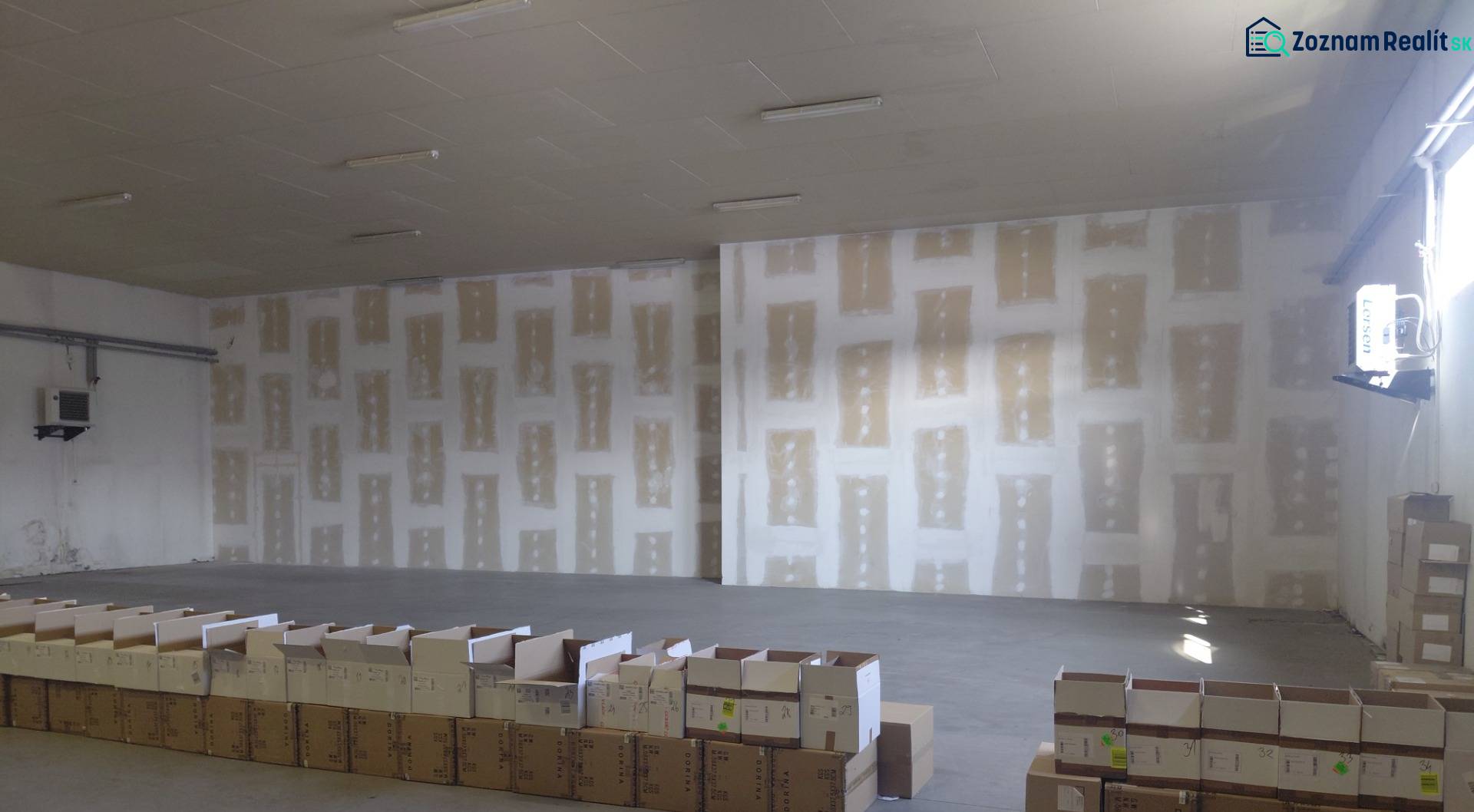 Empty warehouse with concrete floor and scattered cardboard boxes.