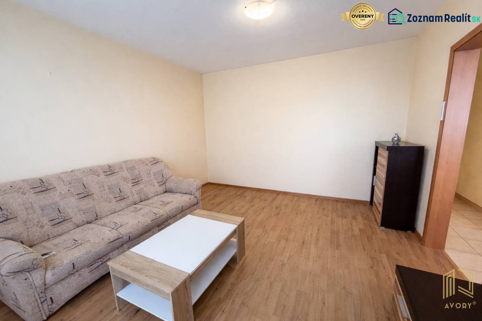 Living room with a sofa, table, and wooden decor flooring in a 2-room apartment.