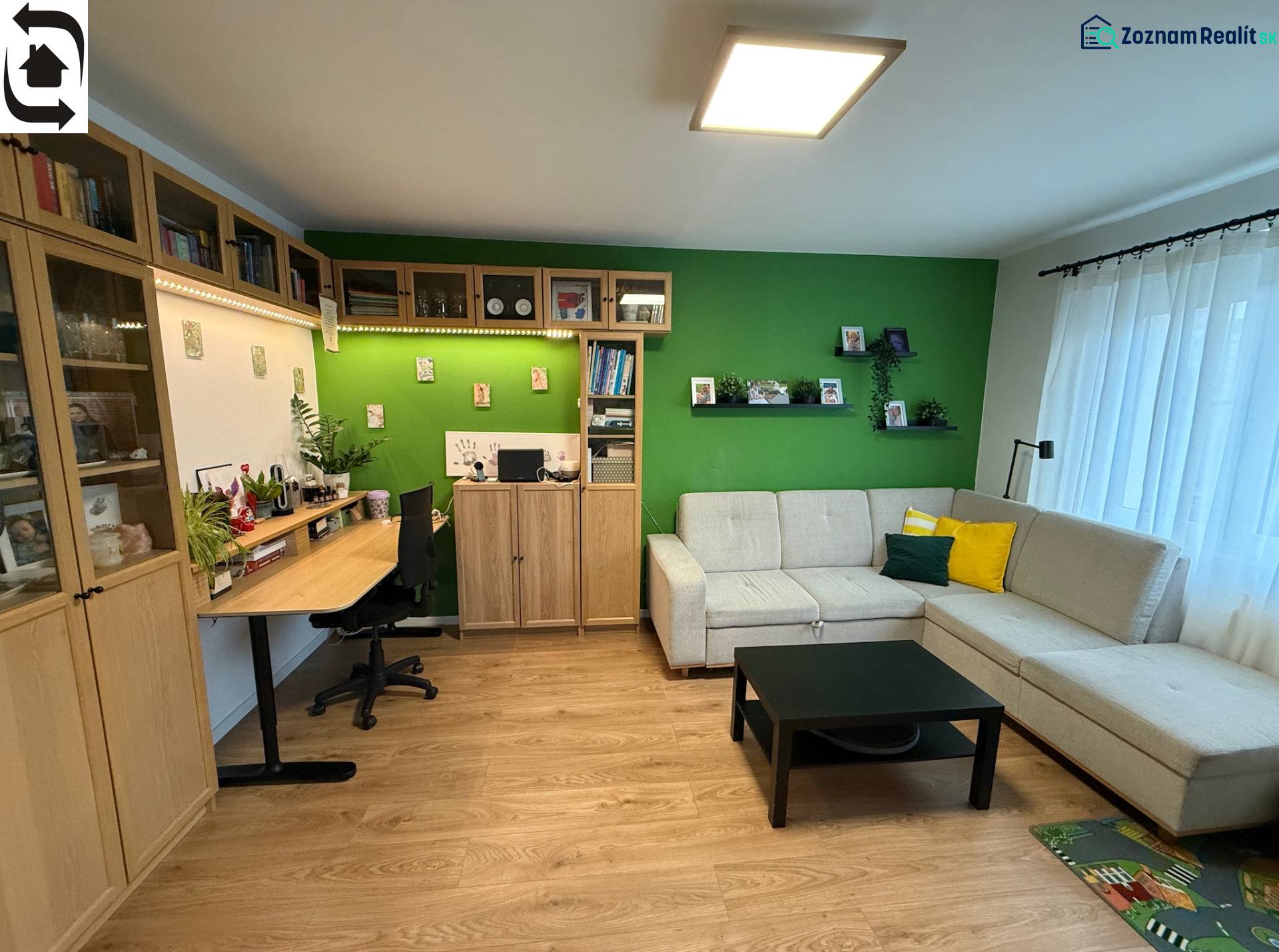 Living room with a sofa, a desk, and a wooden decor floor in a 4-room apartment.