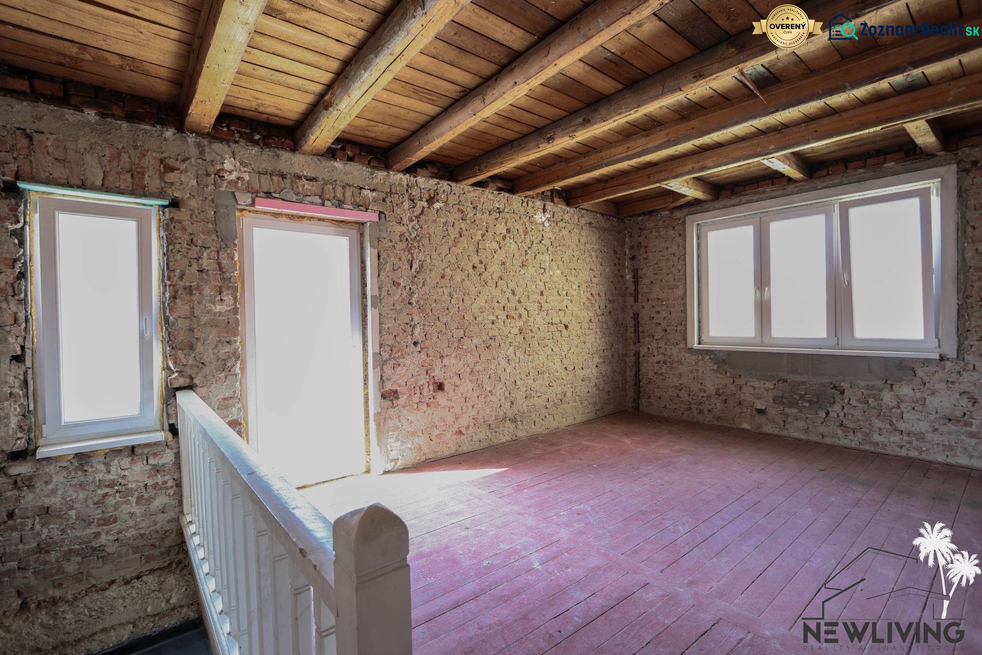 The interior of a family house with bare brick walls, a wooden ceiling, and floor.