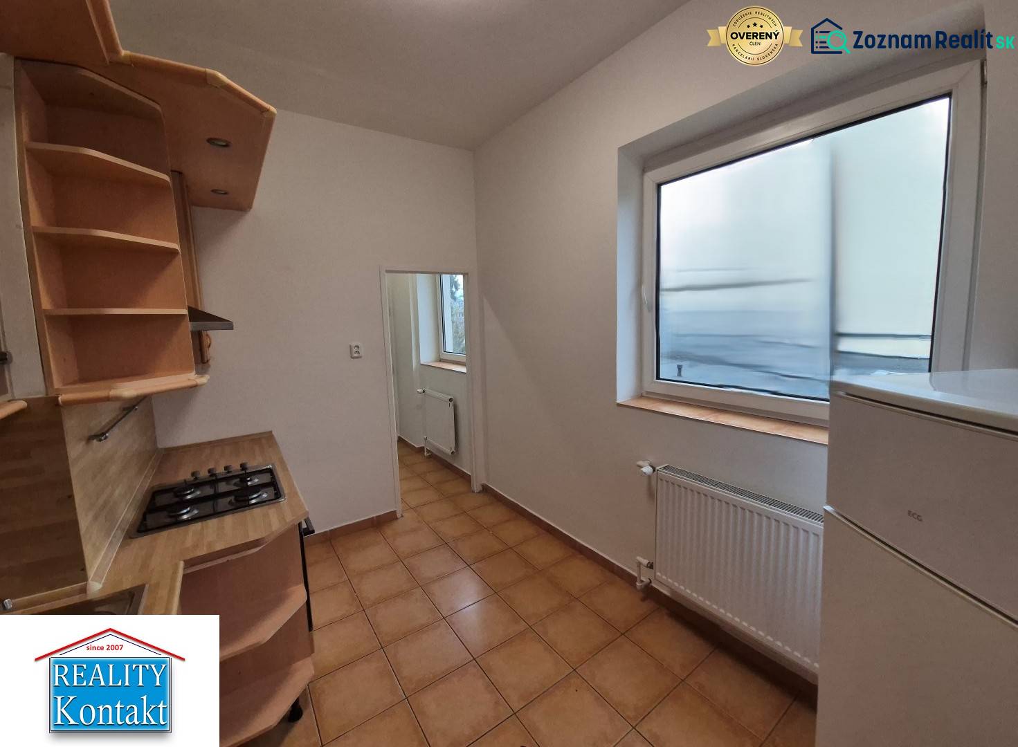 A kitchen in a 3-room apartment with tiles and a large window, light walls, wooden shelves.