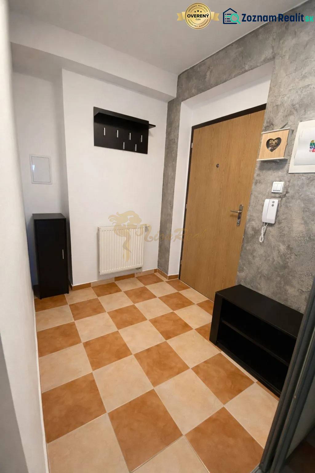 Hallway of a 3-room apartment with tiles, a coat rack, and wooden doors.
