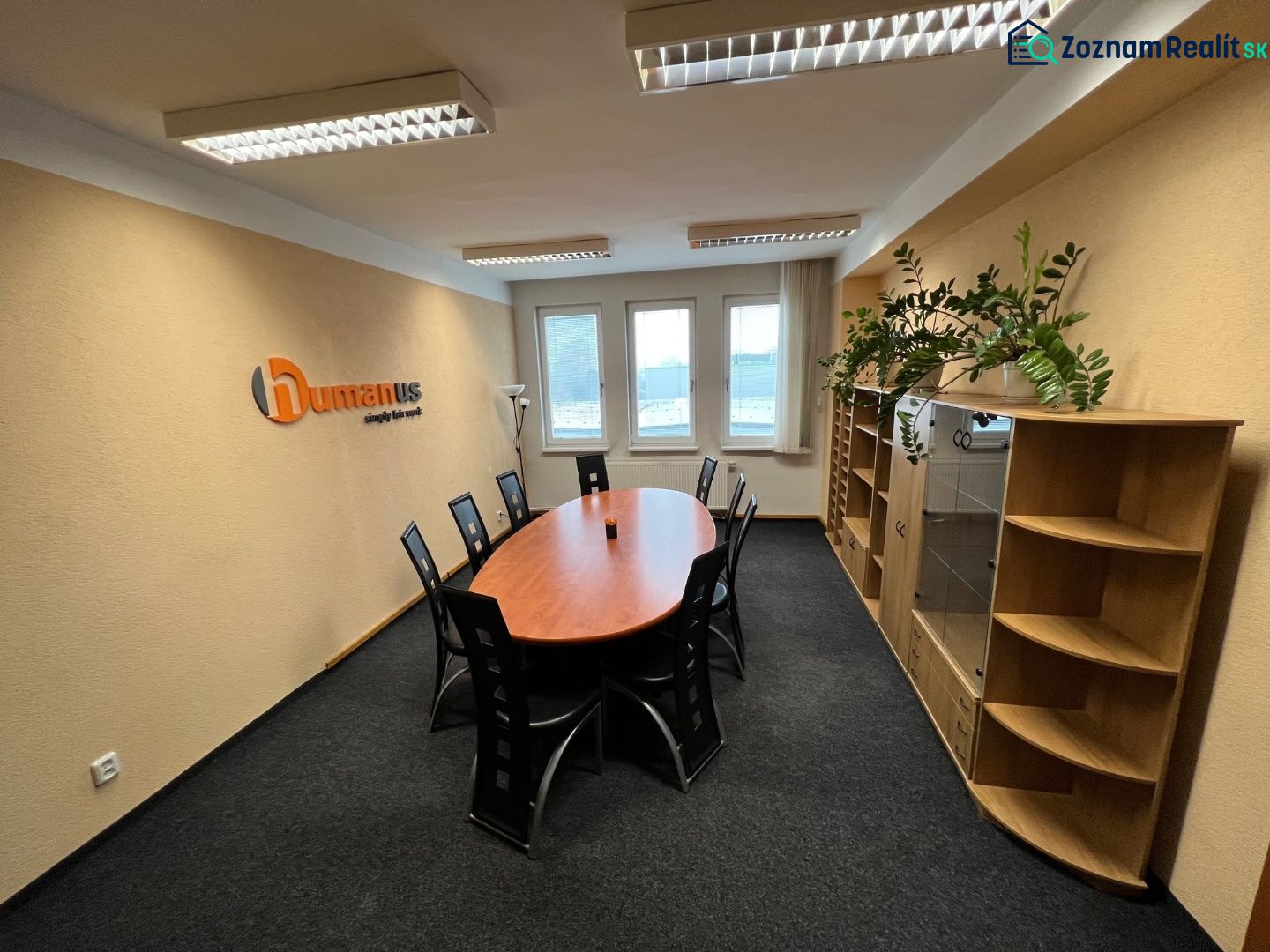 Offices with an oval table, black chairs, and wooden decor furniture.