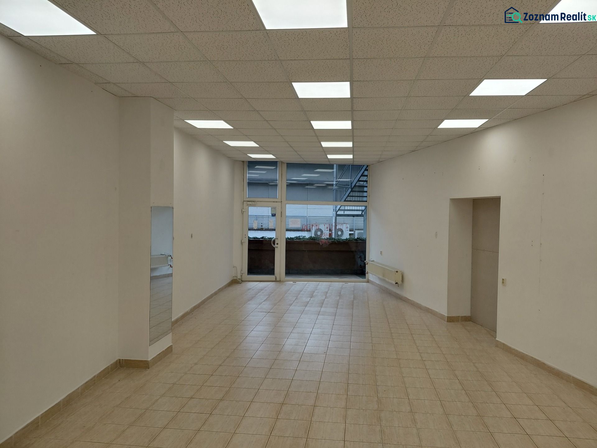 Commercial spaces with white walls, wood-patterned flooring, and large windows.