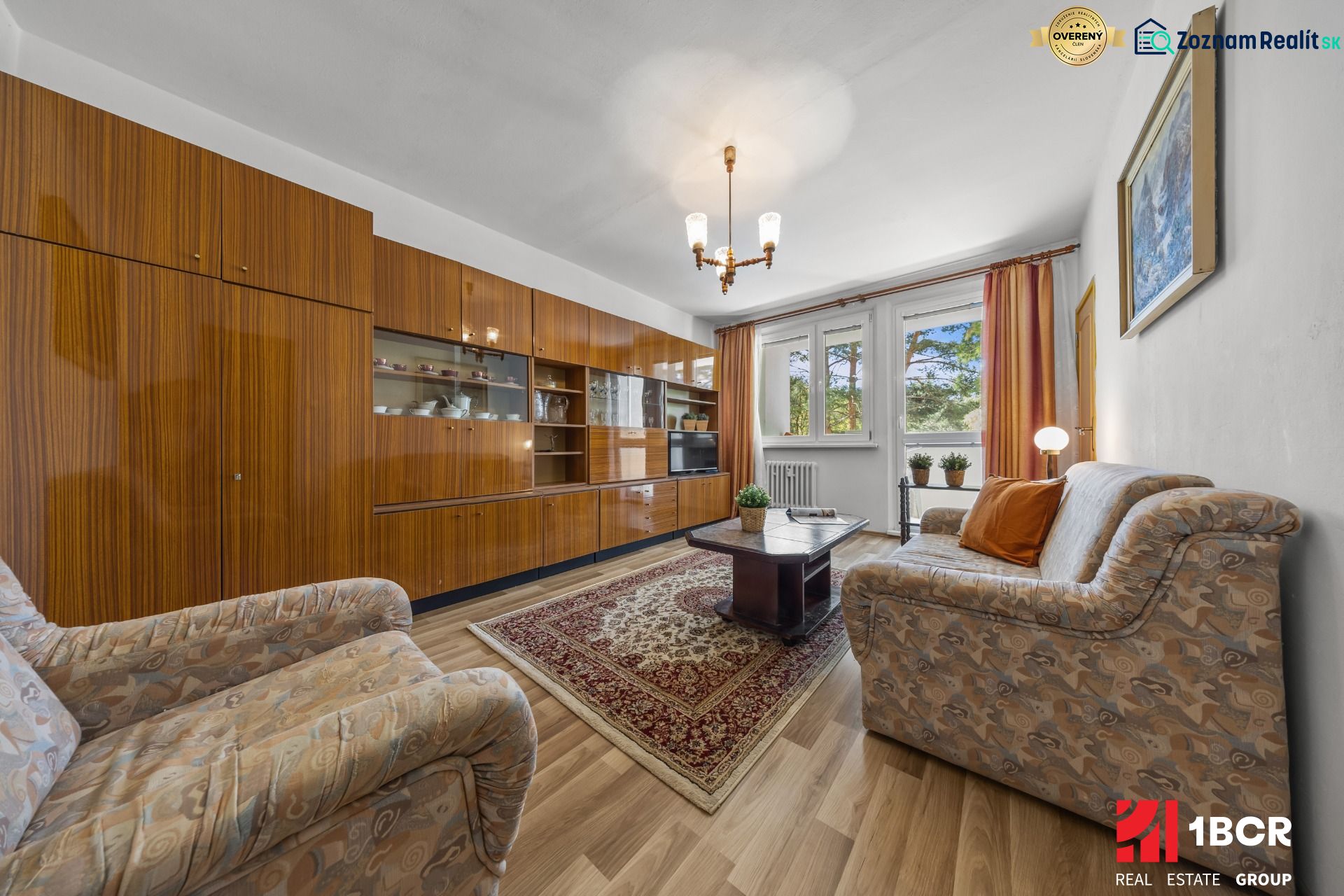 Living room in a 3-room apartment with older furniture and a wooden decor floor.