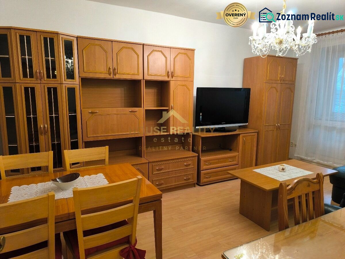 Living room in a 3-room apartment with wooden furniture and a chandelier, floor with wooden decor.