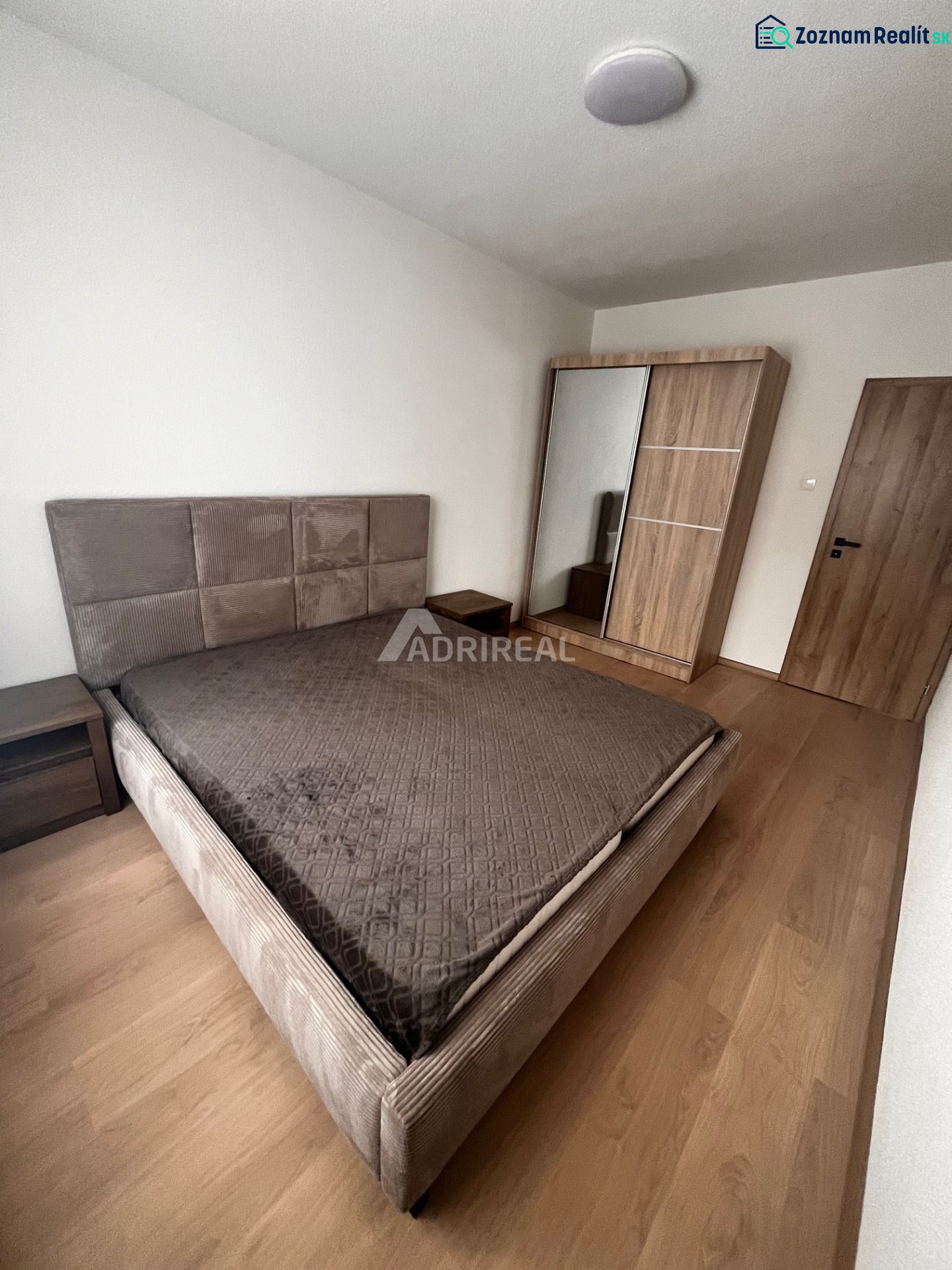 Bedroom in a 2-room apartment with a bed and a wardrobe, floor with wood decor.