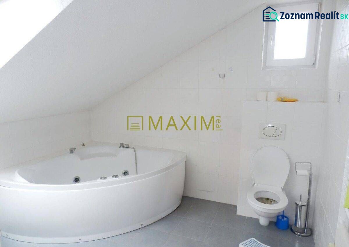 Bathroom with a bathtub and toilet in a cottage with an attic, white tiles.