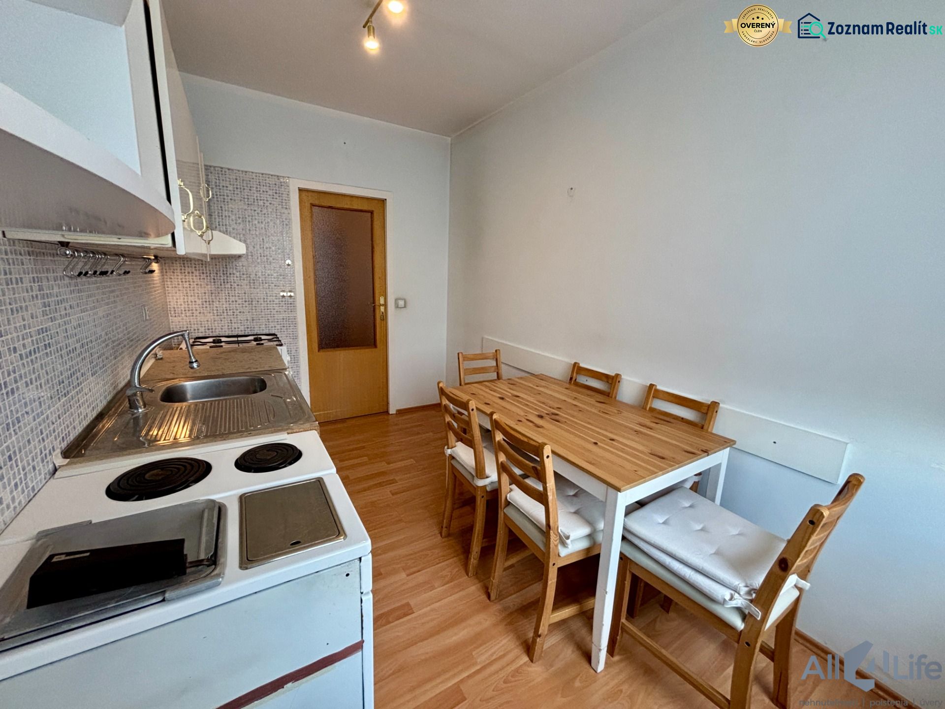 A kitchen in a 3-room apartment with a dining table and a floor with a wooden decor.