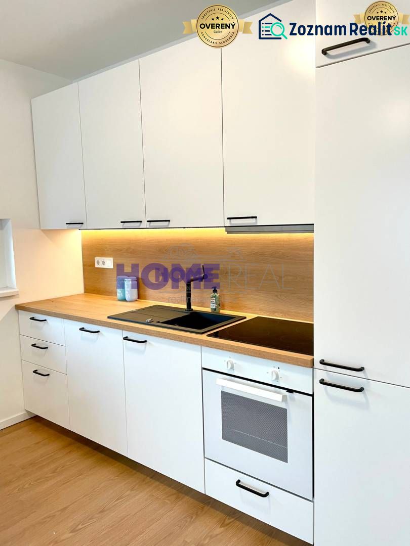 A kitchen unit with light cabinets and a wooden decor floor in a 3-room apartment.