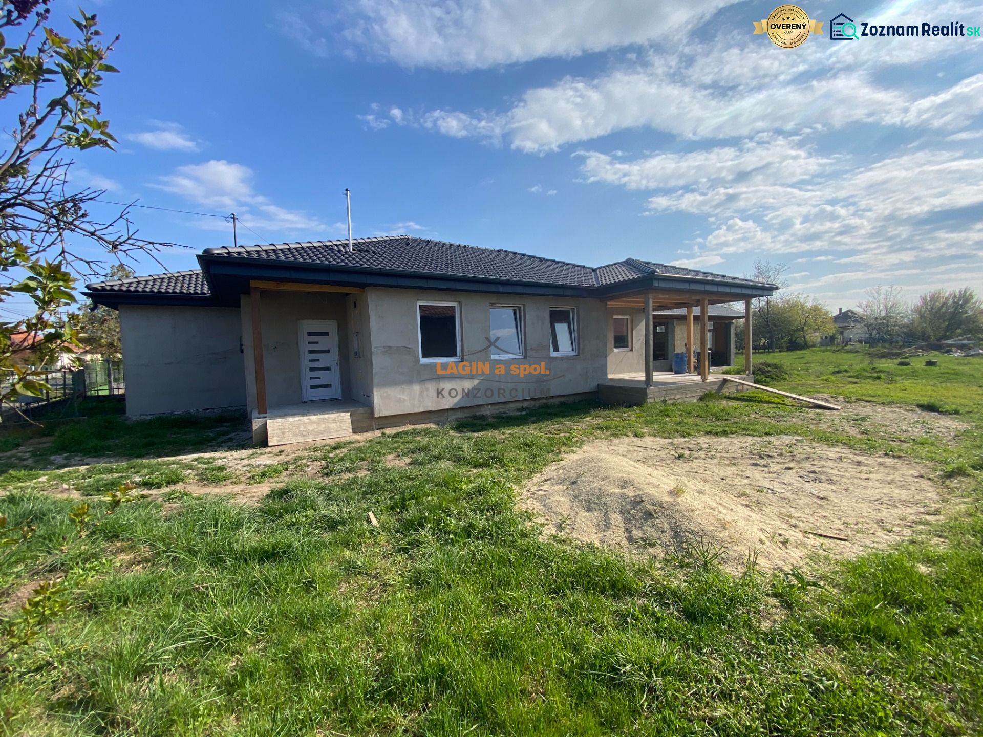 A family house in Encs with a porch on a spacious lawn under a clear sky.
