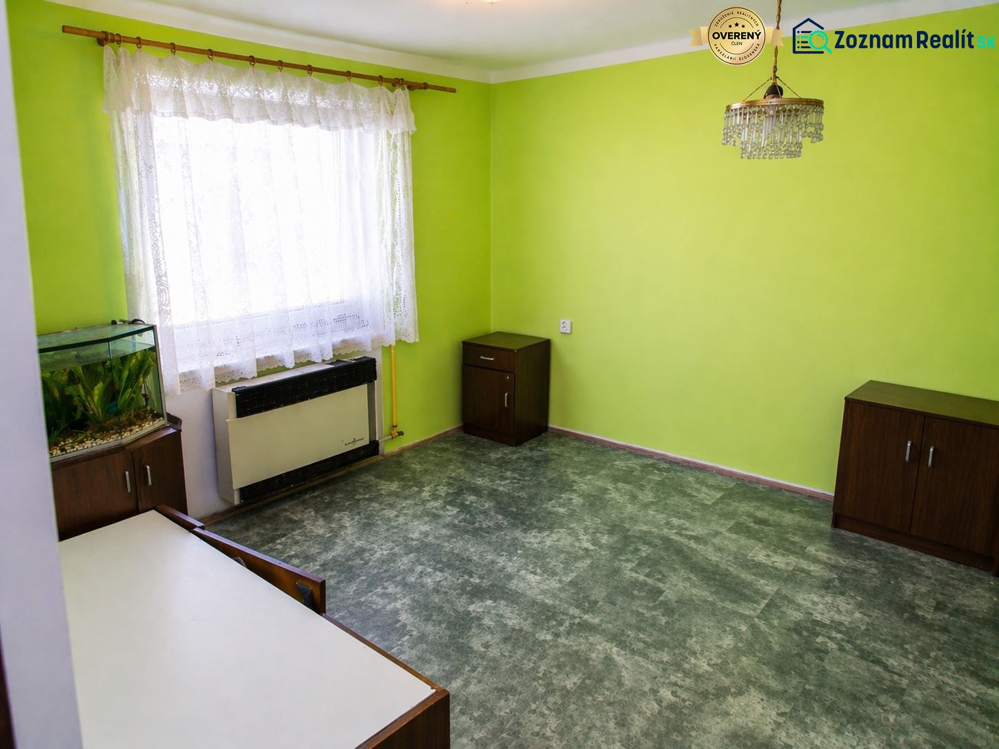 A green-painted room with an aquarium, curtains, and a chandelier in a 3-room apartment.