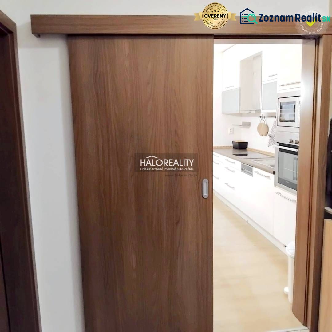 A kitchen with built-in appliances in a 2-room apartment, separated by wooden sliding doors.