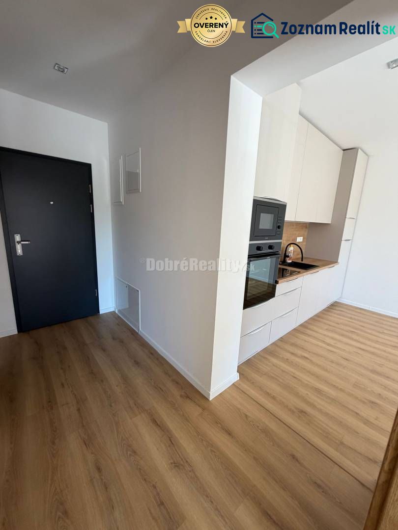 Entrance to a 2-room apartment with a kitchen, wooden decor flooring, white cabinets.
