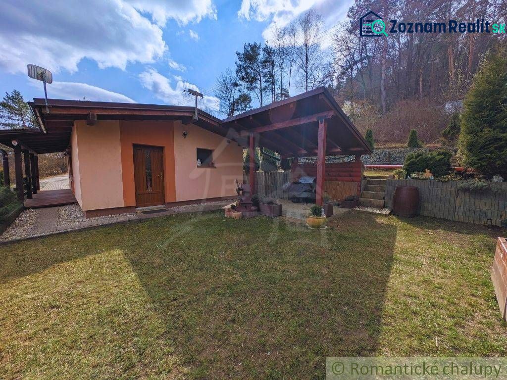 A cottage in Kvakovce with a lawn and a gazebo, bordered by trees and a forest backdrop.