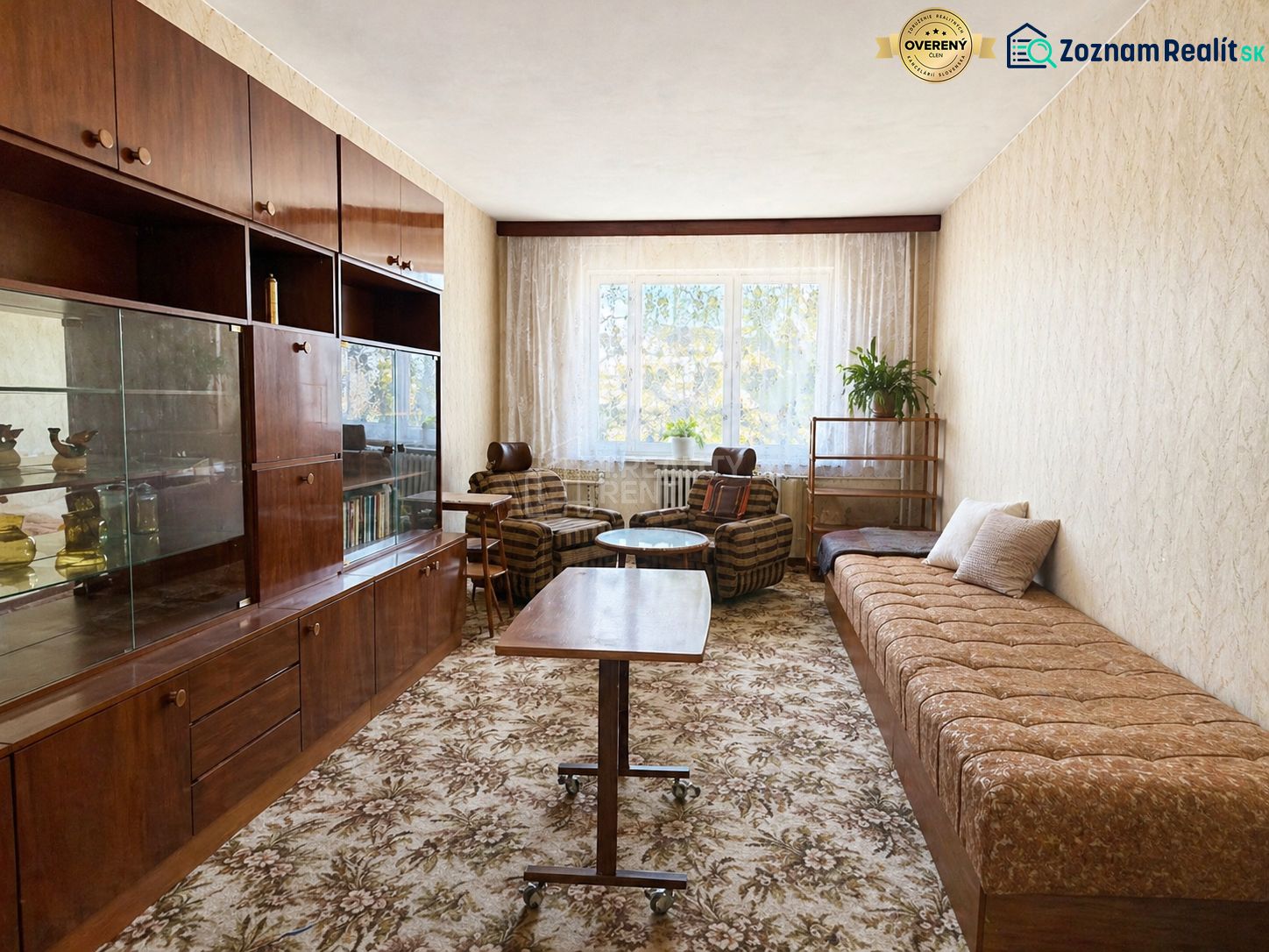 Living room in a two-room apartment with a sofa, table, and dark wood furniture.